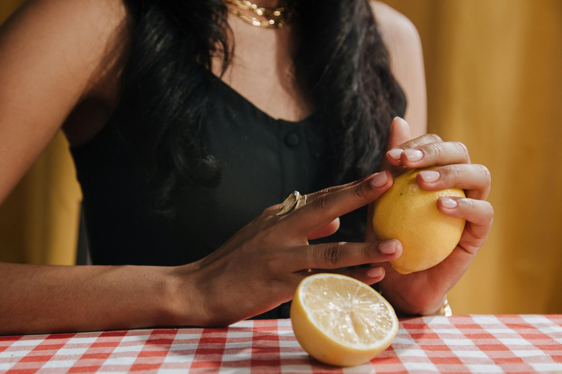 Eine Hand hält einen orangen Vibrator gegen einen minimalistischen lila Hintergrund
