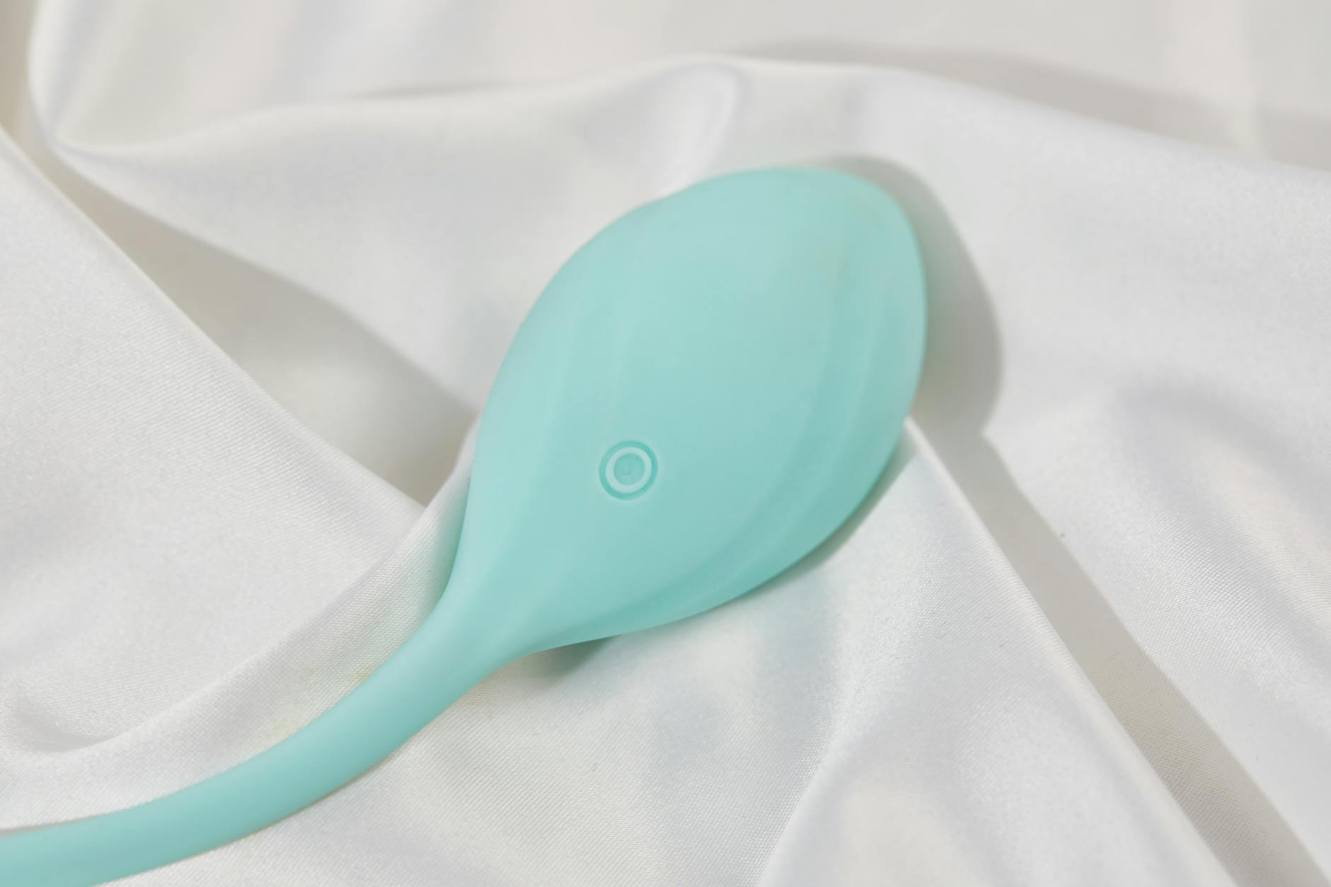 A stylish teal vibrator on smooth white silk fabric, perfect for intimate wellness moments