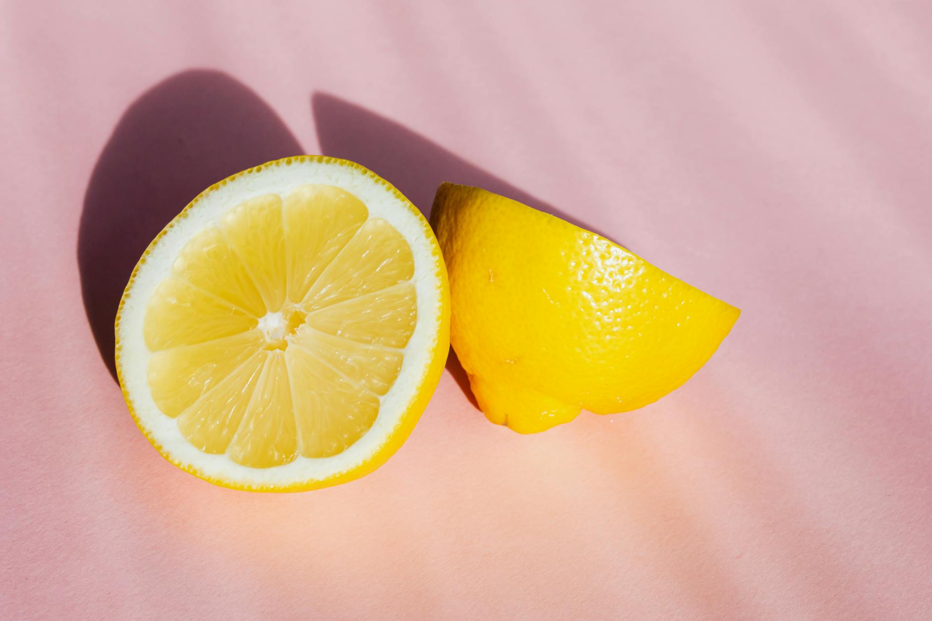 Frische Zitronenhälften auf rosa Hintergrund in Sonnenstrahlen, symbolisiert neue Intensität nach Jahren der Partnerschaft