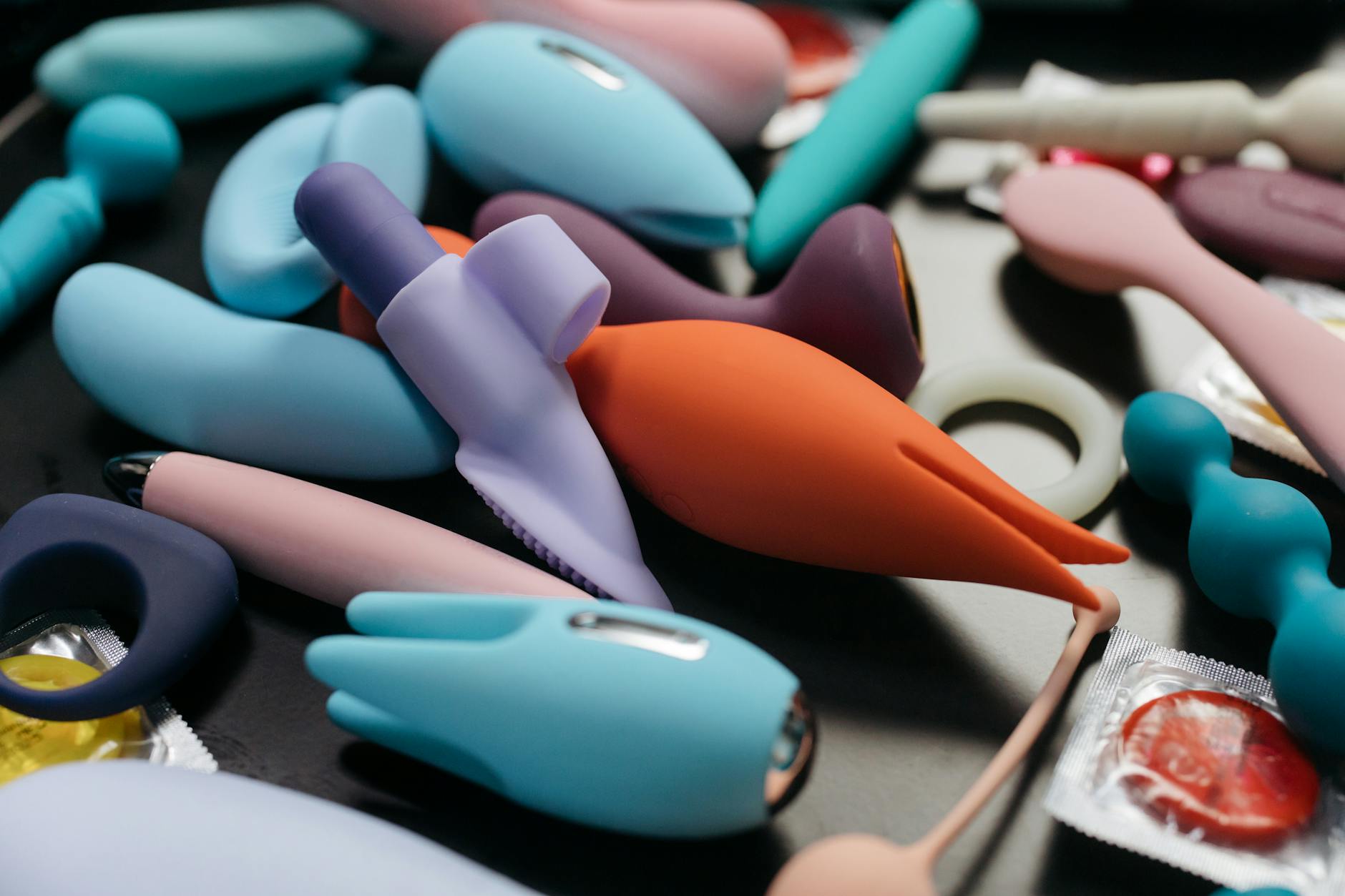 Ein blaugrüner Silikonvibrator in einer Hand vor violettem Hintergrund, Symbol für Selbstliebe und Sexualität