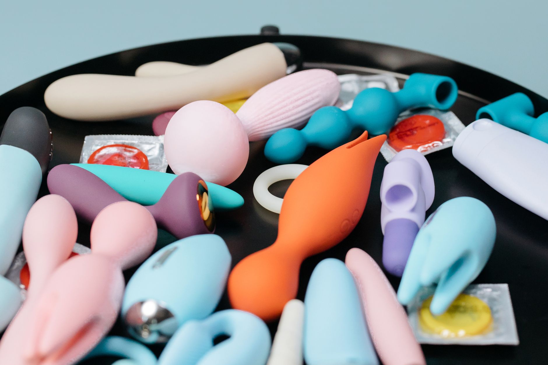 Hand hält einen modernen orangefarbenen Vibrator vor purpurnem Hintergrund
